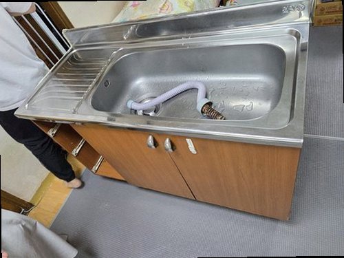 금천구 누수탐지 싱크대 하부장 안쪽과 젖은 벽면을 확인하는 모습